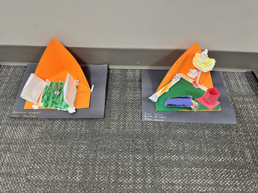 Two third-grade 3D playground models created with colorful paper, felt, clay, and craft materials. One includes a soccer goal and field, while the other shows several pieces of redesigned playground equipment.