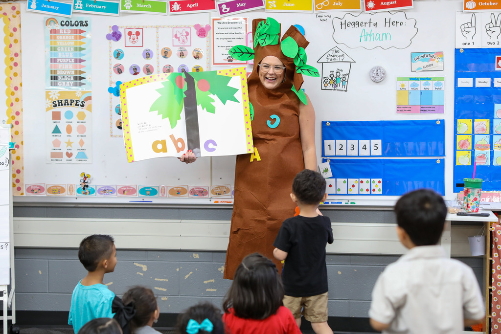 A teacher dress as a tree stands in front of a classroom.