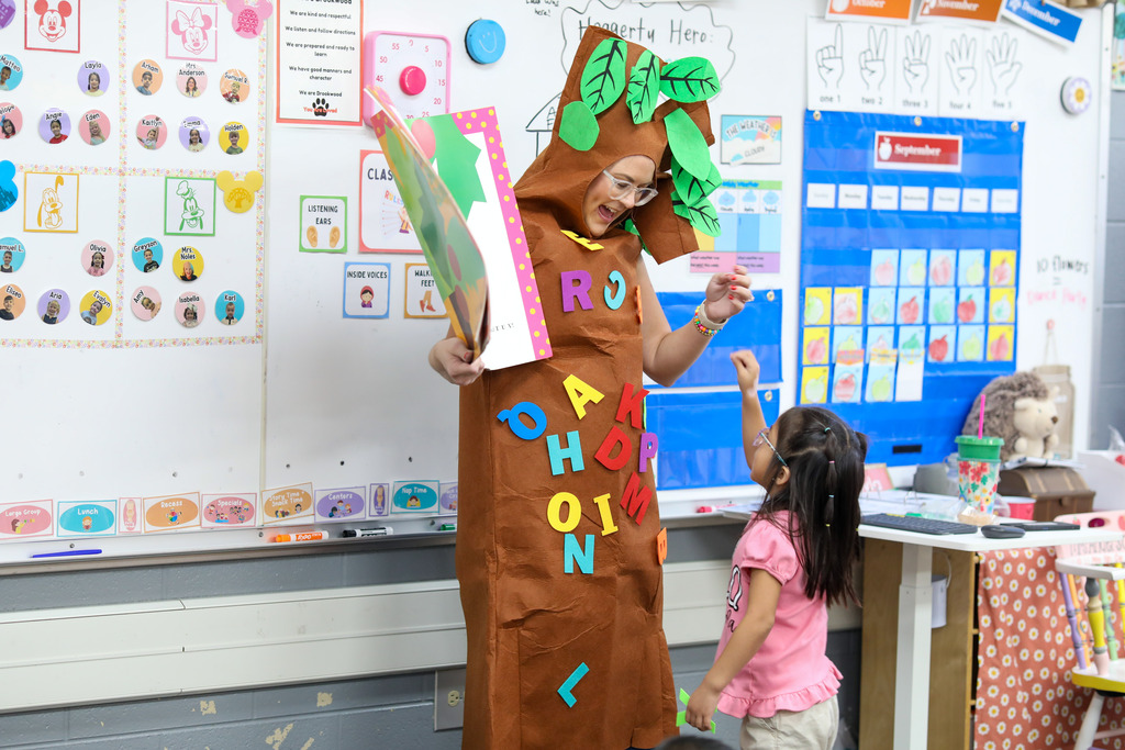 A teacher dress as a tree stands in front of a classroom.
