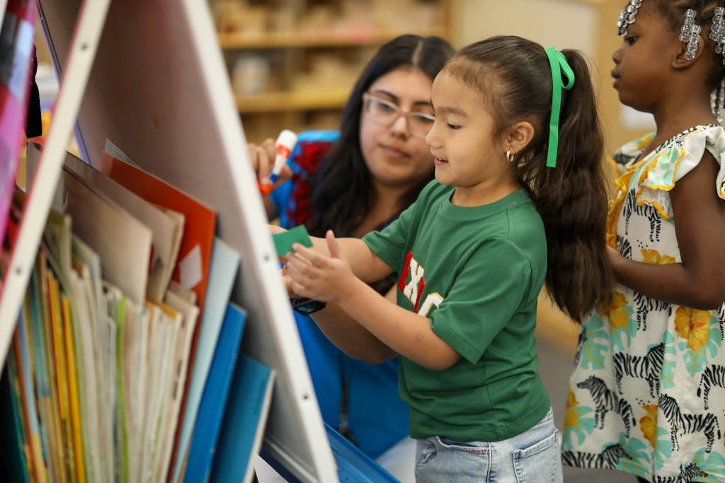 A girl places her paper on a flat piñata.