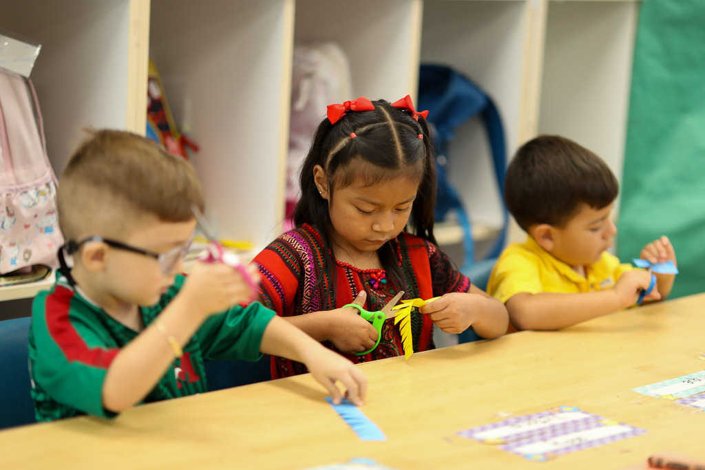 A girl cuts strips into a piece of paper.