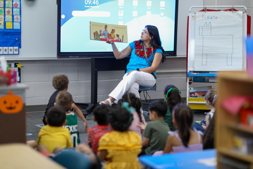 A teacher reads a book to a class of students.