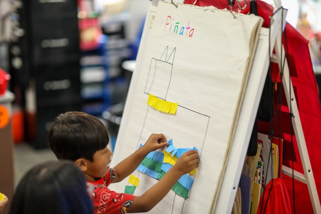 A boy places paper on a flat piñata.