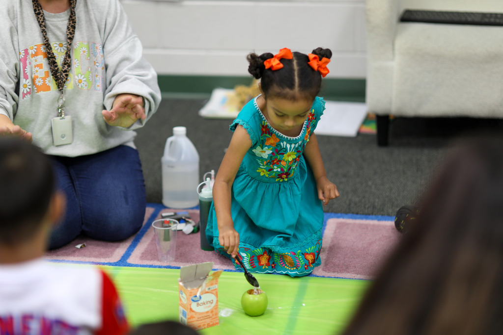A young girl adds baking soda to her apple.