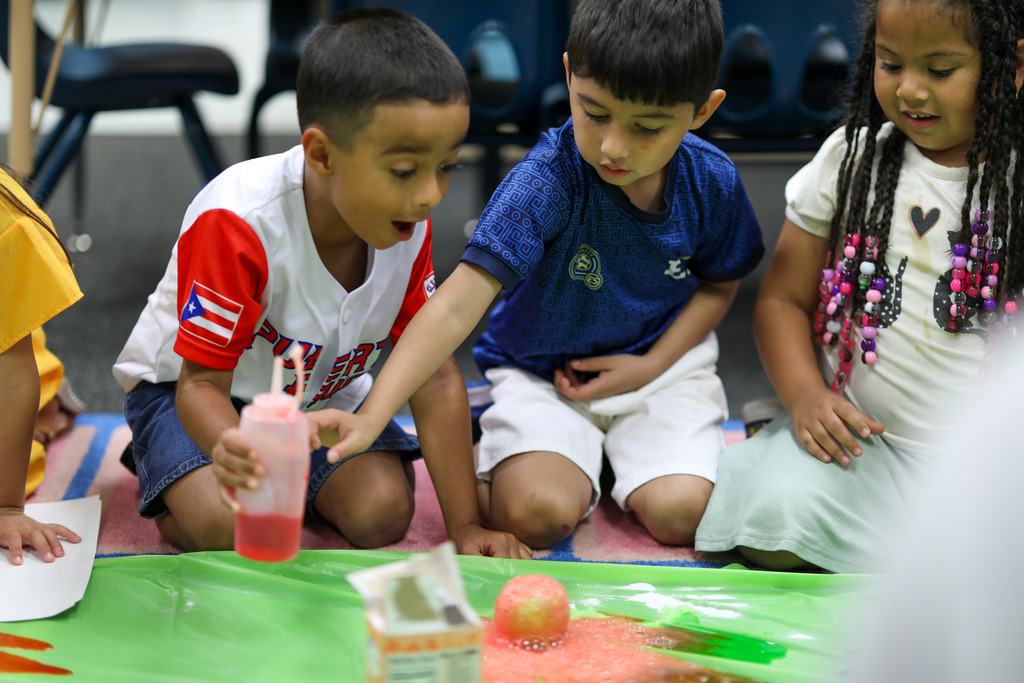 Students pour vinegar into their apple experiment.