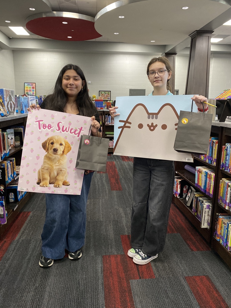 Two students hold Book Fair raffle prizes and winner posters after being selected as winners of the HCMS Scholastic Book Fair raffle. The students are recognized for participating in the Book Fair and are pictured with their prize packages.