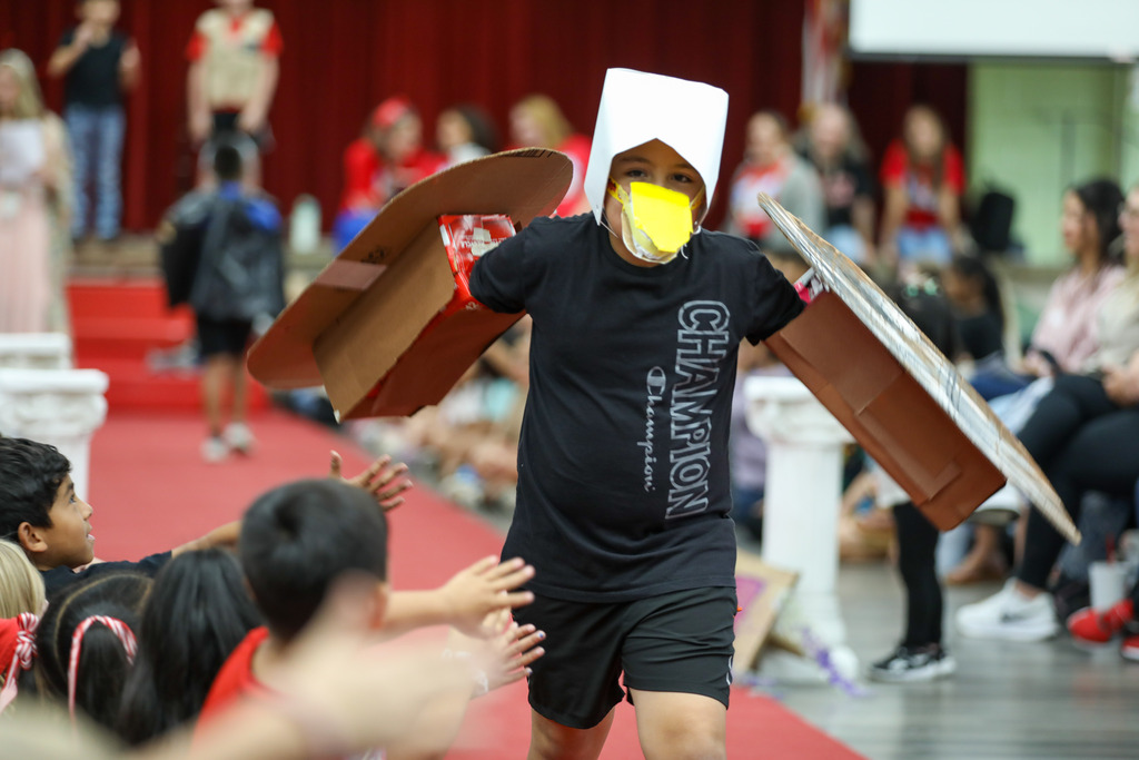 students smiling and walking in a runway fashion show using recycled materials