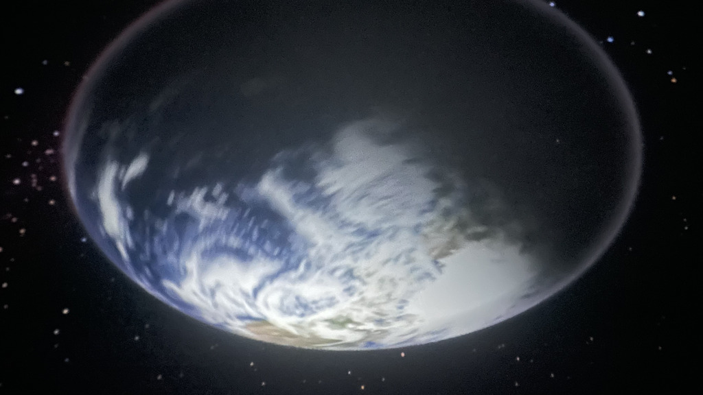 A full-screen projection of planet Earth in space surrounded by stars, displayed on a planetarium dome.