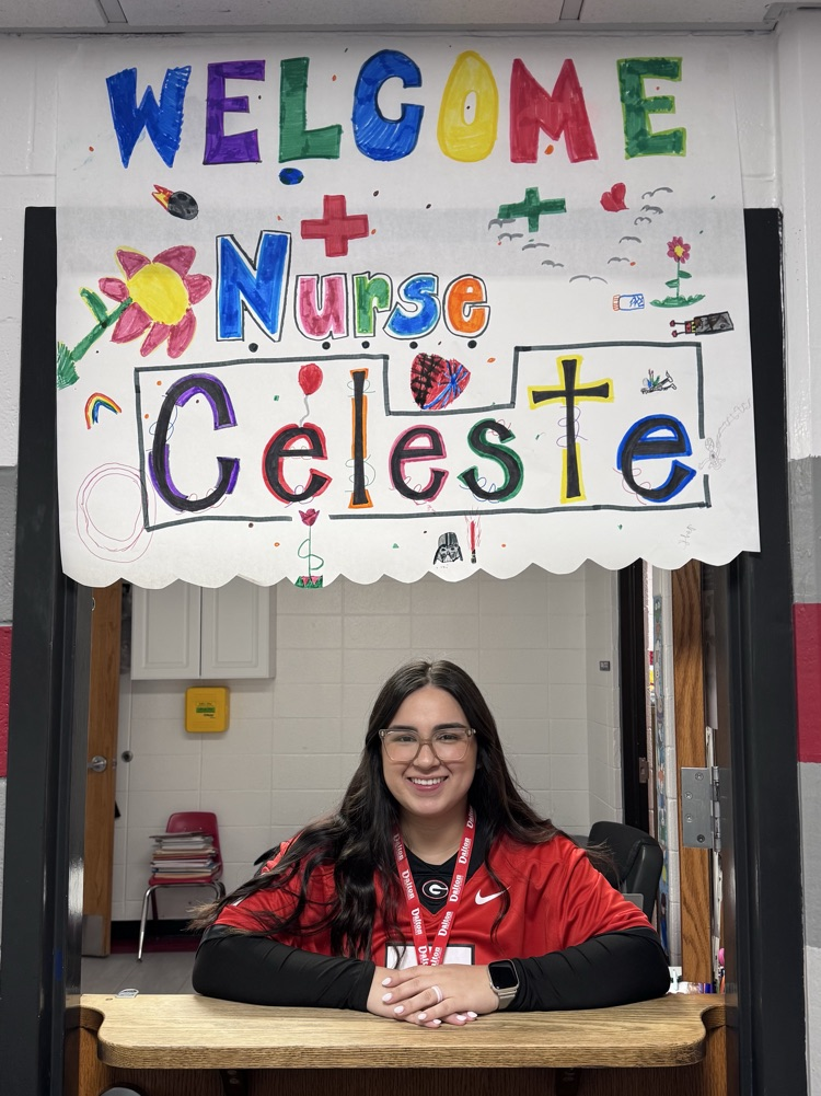 A nurse standing on at the door under a sign that says “Welcome Nurse Celeste"