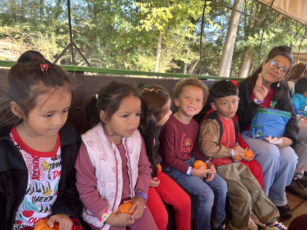 preK students seated while on a hayride with their teacher