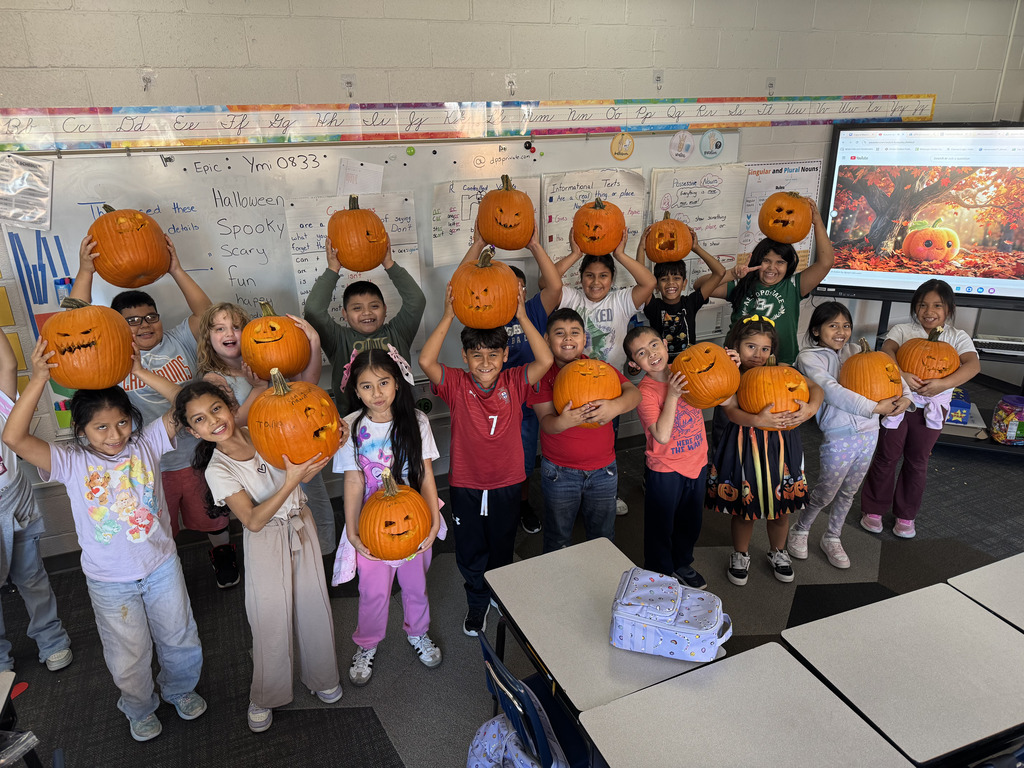 class photo of students holding their individually carved pumpkins