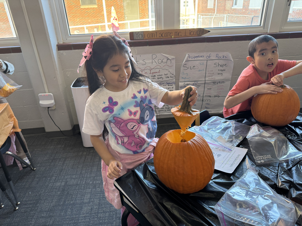a girl carves a pumpkin while a boy watches