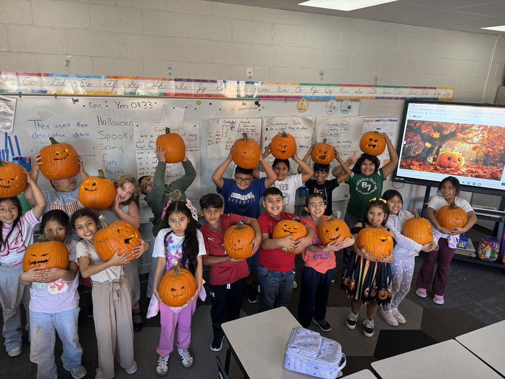 class photo of students holding their individually carved pumpkins