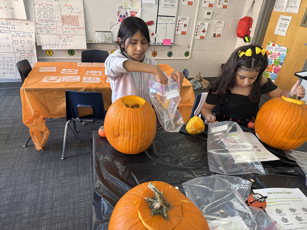 two students work at a table to carve their own pumpkins three students work at a table to carve their own pumpkins