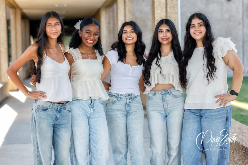 a group of girls smile int heir white shirts and jeans