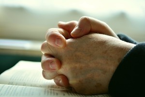hands folded on top of a Bible