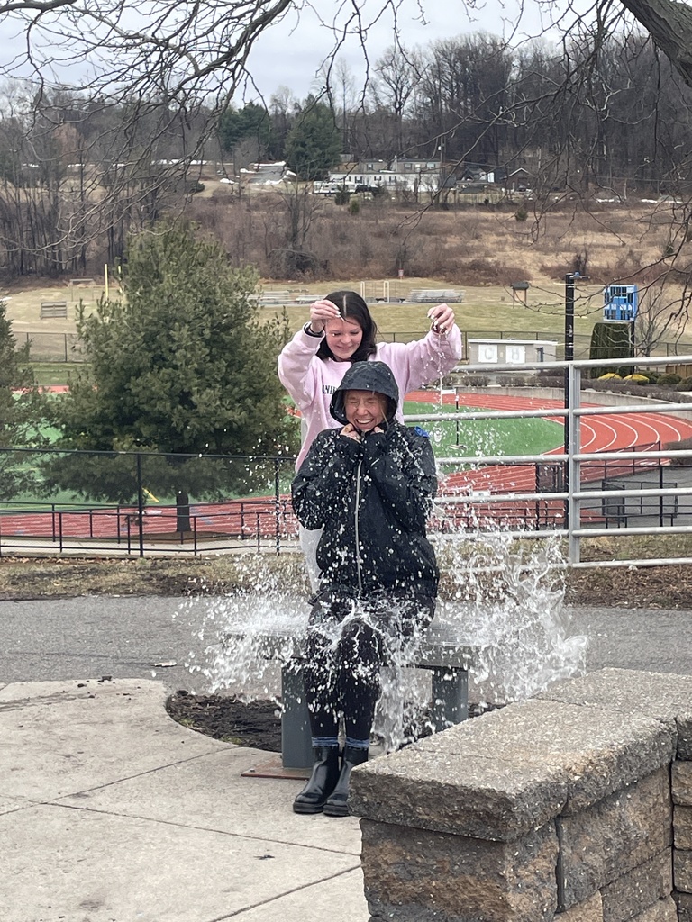 Student popping a water balloon over Miss Adams' head.