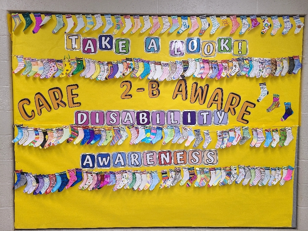 Bulletin Board titled Take a Look! Care 2-B Aware Disability Awareness with paper socks decorated by students.