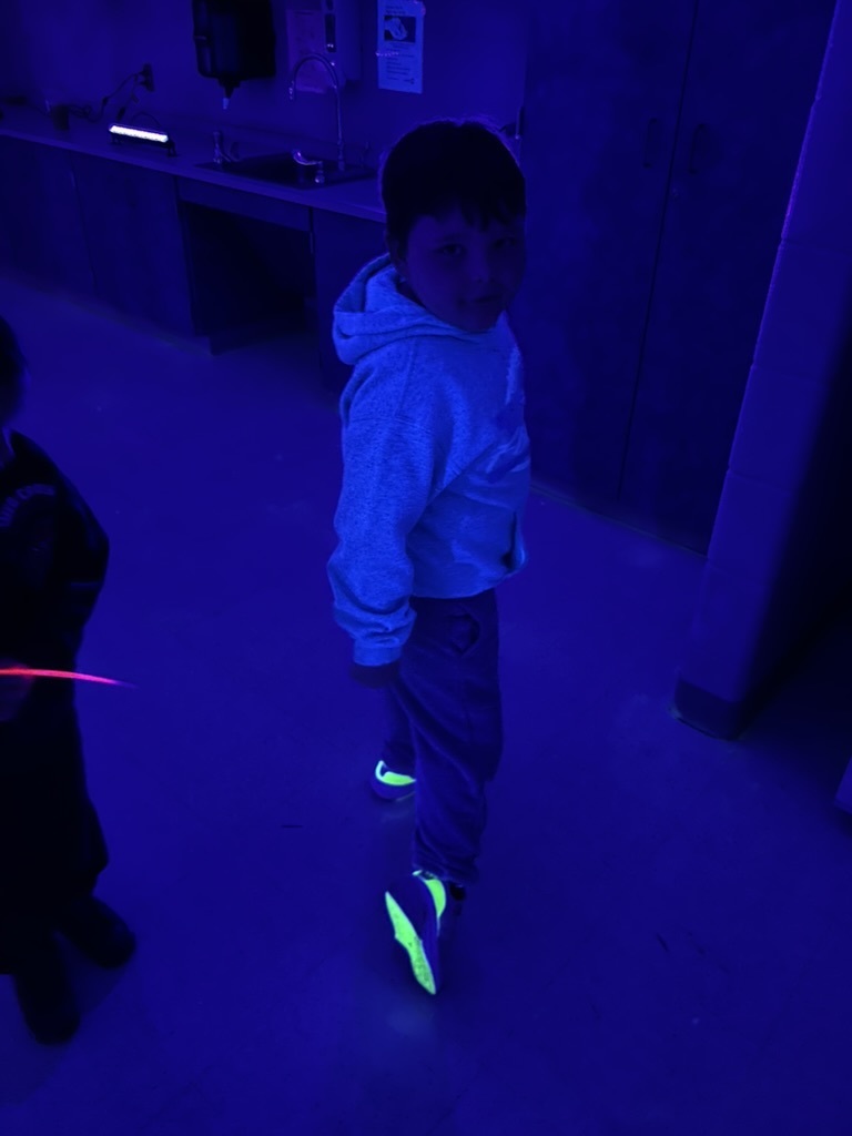 Blacklight picture of a student whose sneakers glow under black light