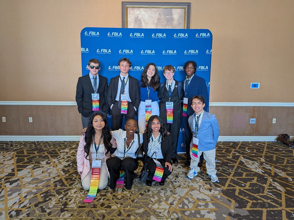 Nine students standing in front of an FBLA step and repeat sign at state competition