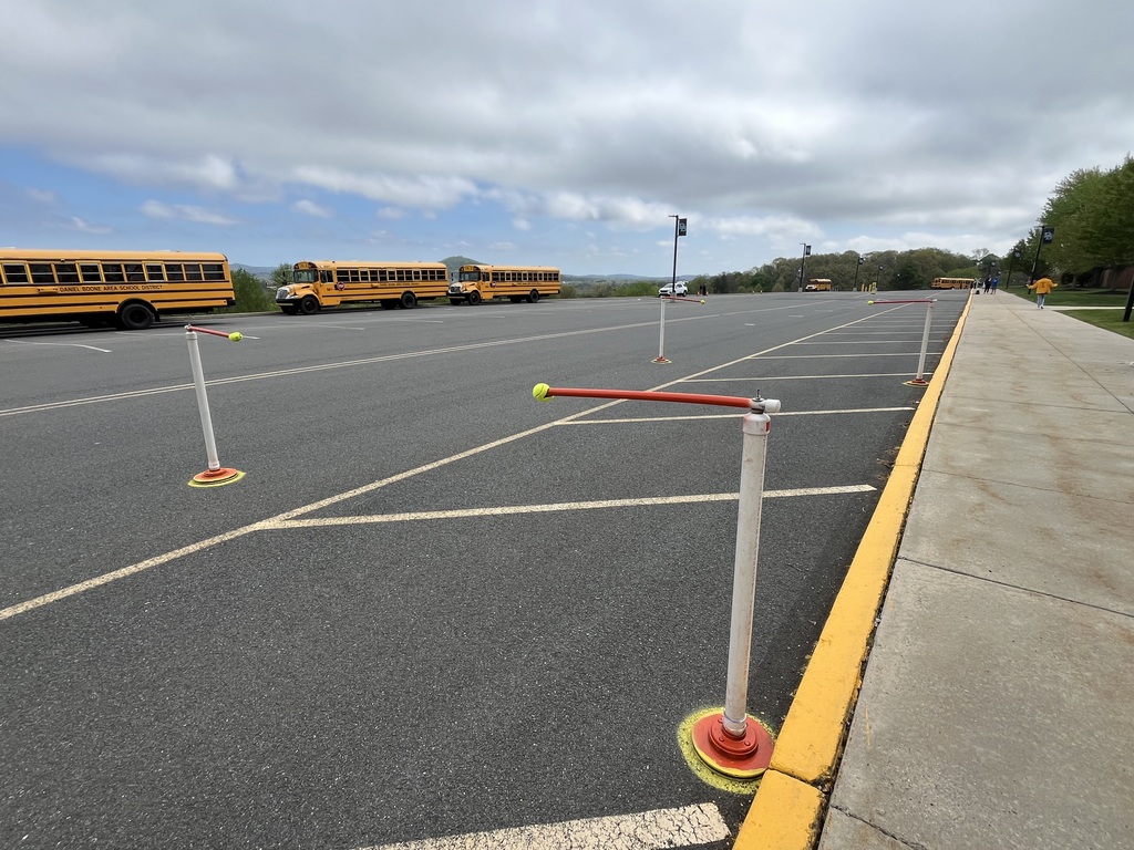 Three buses driving in parking lot with pylon course setup for maneuvering buses through.