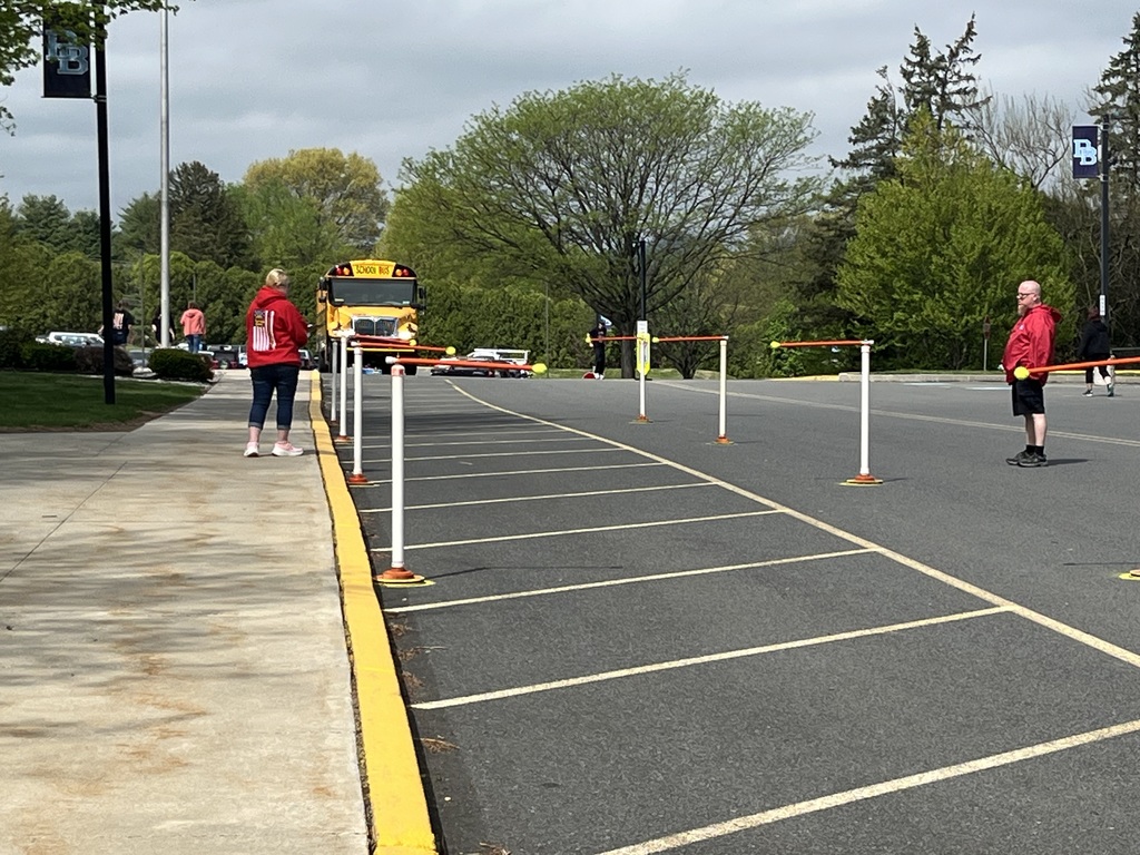 One bus about to maneuver through pylons in school parking lot