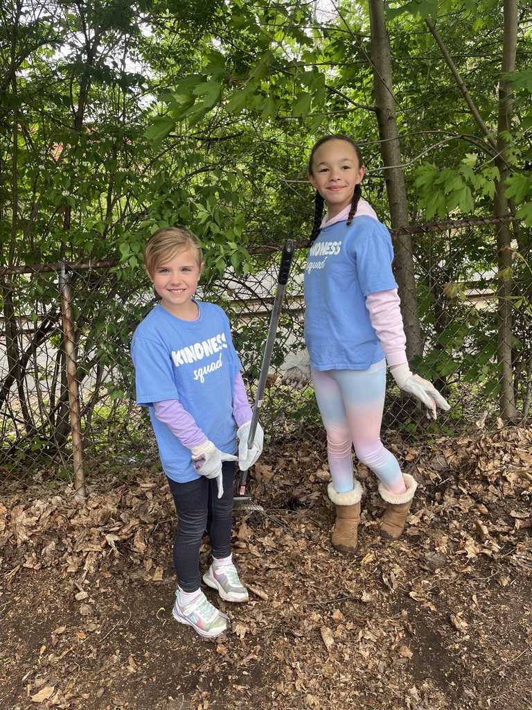 Two students wearing their blue KINDNESS SQUAD Tshirts wearing work gloves and holding a rake
