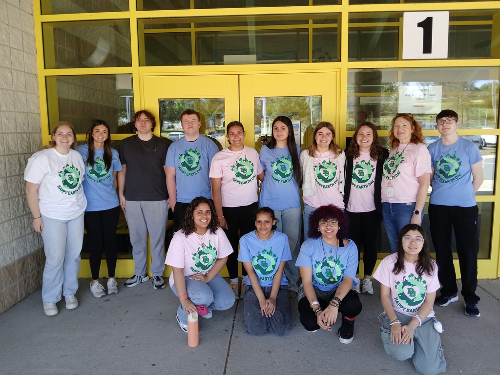 Picture of 14 students and staff Happy Earth Day shirts in pink and blue colors standing outside of the Primary Center.