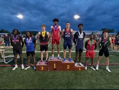 Eight students standing on the football field wearing medals.