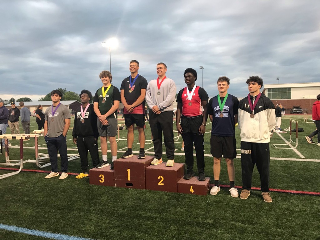 Eight students standing on the football field wearing medals.