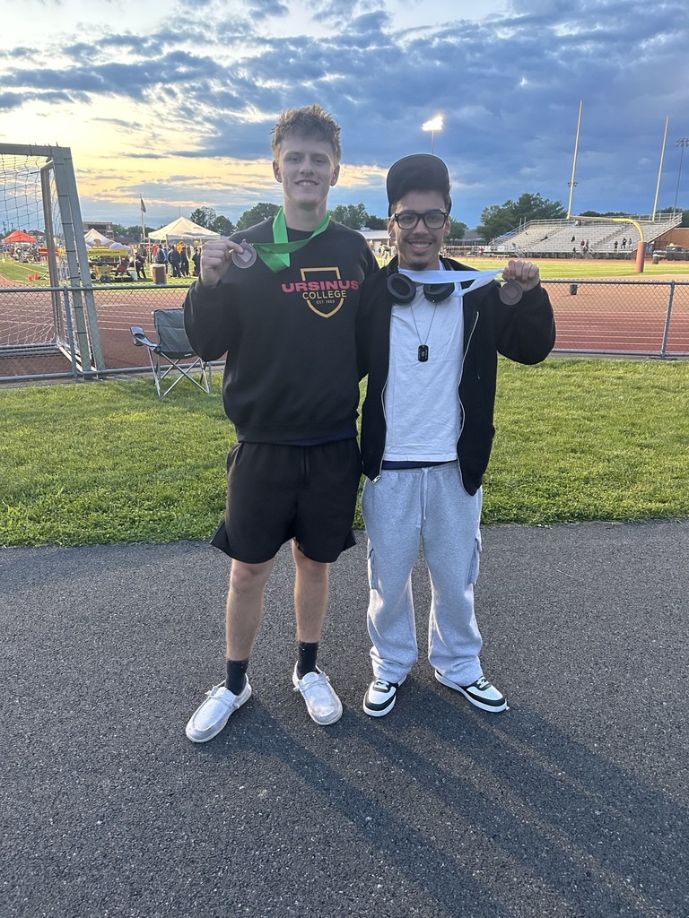 Two boys standing outside holding medals