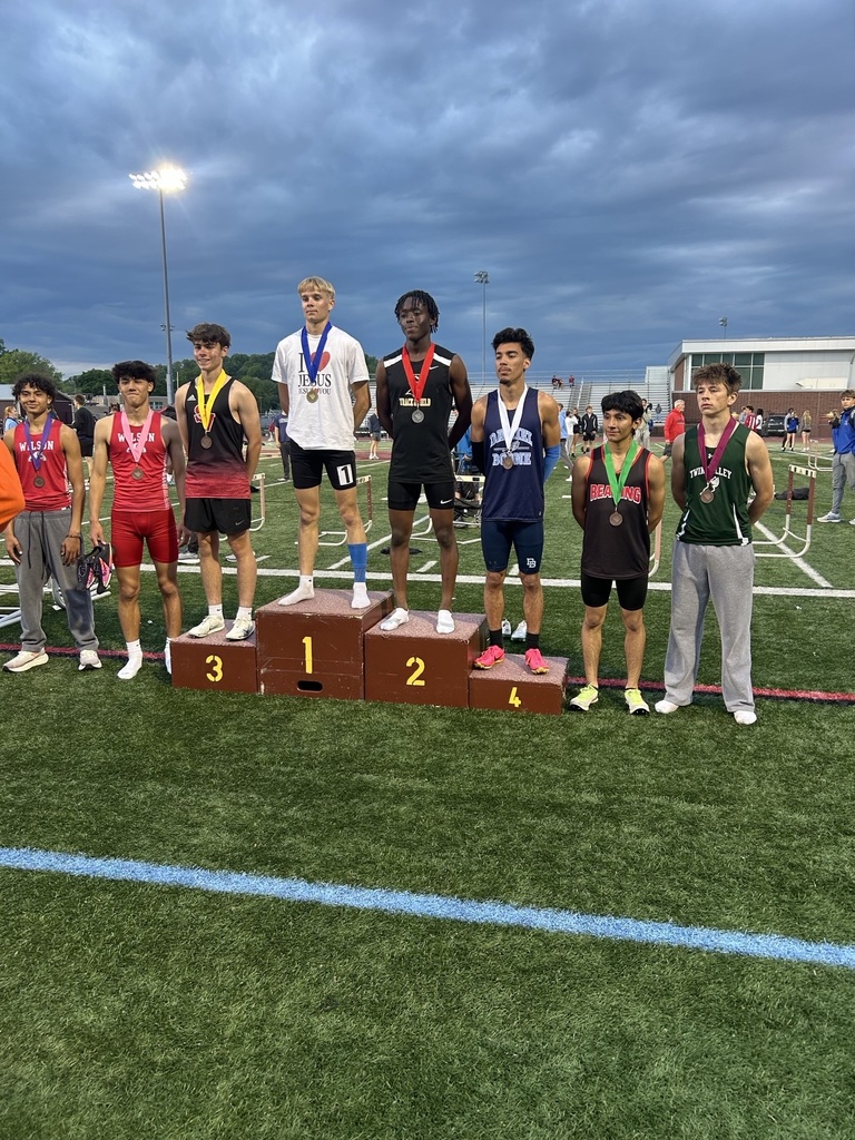 Eight students standing on the football field wearing medals.