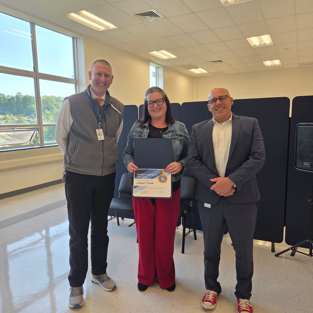 Principal Aaron Sborz standing with Special Education Teacher Jennifer Derrick and Superintendent Tom Voelker. Jennifer is holding a Sweet Impact Award Certificate. The trio are standing in the Daniel Boone Board Room.