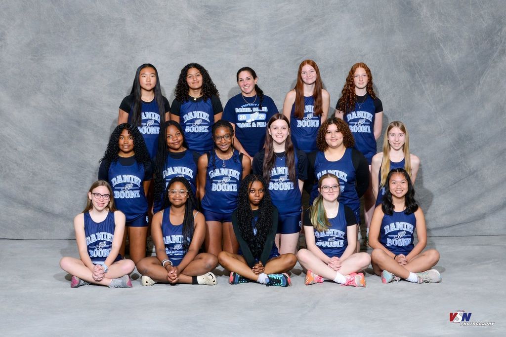 Professional photo of 16 girls wearing their Daniel Boone Track outfits in front of a grey background.