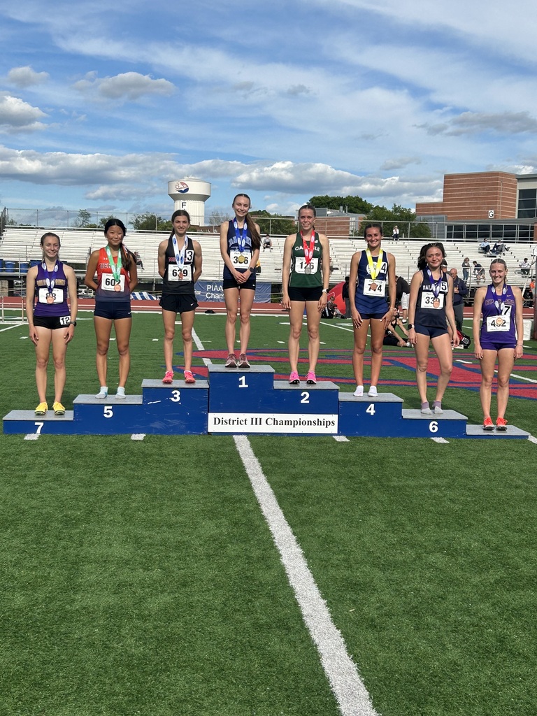 Eight students wearing number bibs and medals standing on a rising podium showing 1st - 8th place in the District III Championships