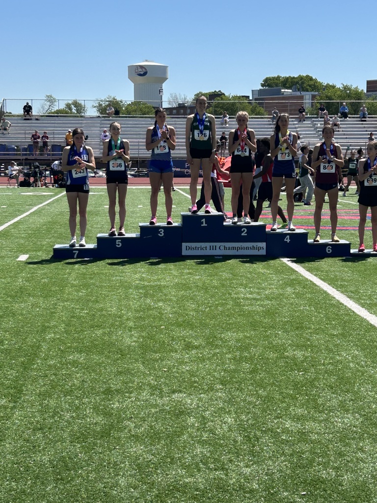 Eight students wearing number bibs and medals standing on a rising podium showing 1st - 8th place in the District III Championships