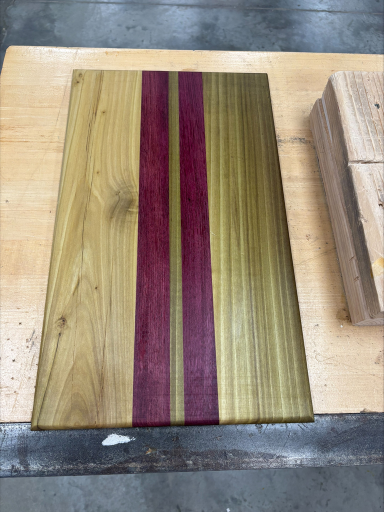 Serving board with two strips of cherry colored wood and medium colored stain on remainder of wood.