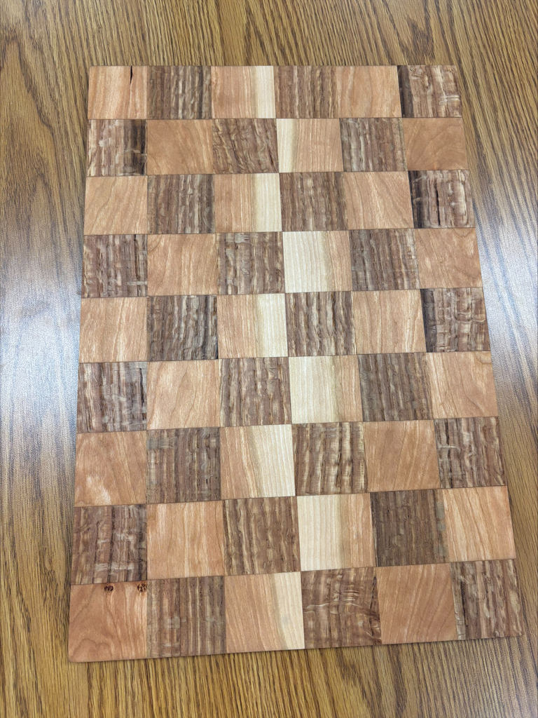 Checkerboard pattern serving board with light and dark pieces of stained wood.