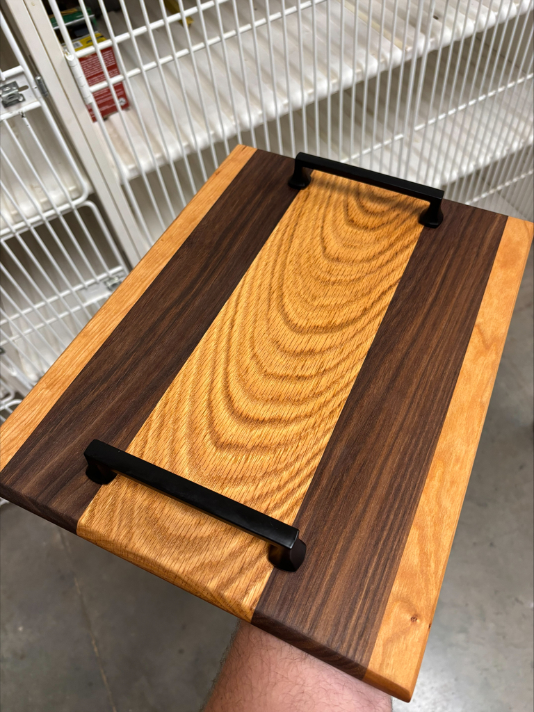 Serving board with medium oak finish and two darker stained pieces as stripes.  Serving piece also has black metal handles.