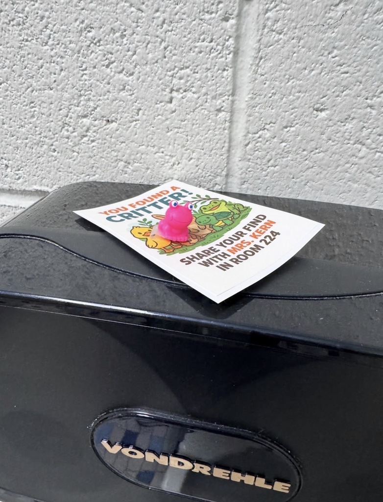 Small pink rubber frog sitting on a note that reads You Found A Critter! Share your find with Mrs. Kern in Room 224.