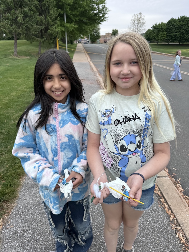 Two students picking up trash in the parking lot.