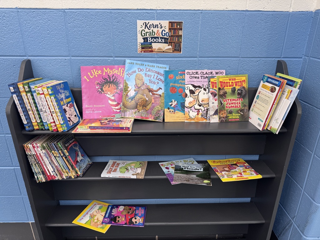 Kern's Grab & Go Books sign on a blue wall with a book cart filled with free books.