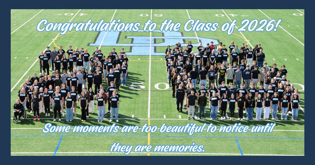 Aerial photo of the Daniel Boone Area High School Class of 2026 standing on the football field and arranged to form the number “26” at midfield. The students are wearing mostly black shirts and are positioned around the large Daniel Boone logo at the 50-yard line. Text at the top reads, “Congratulations to the Class of 2026!” and text at the bottom reads, “Some moments are too beautiful to notice until they are memories.” The image celebrates the graduating senior class and their time at Daniel Boone.