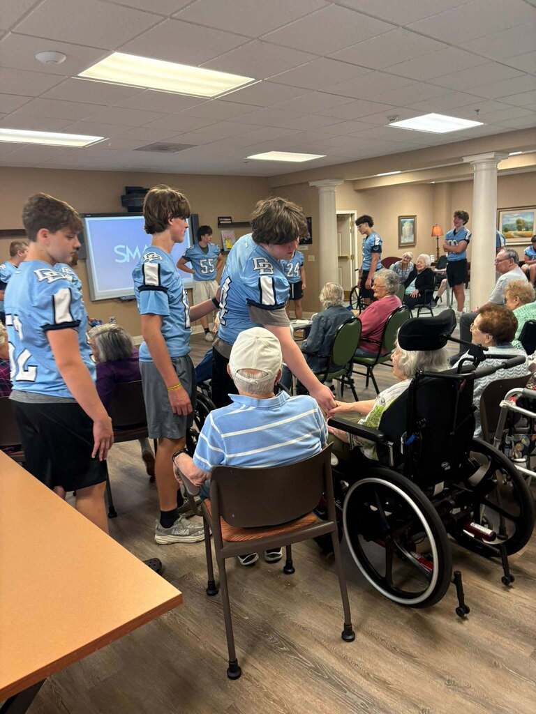 Members of the Boone football team shaking hands with residents of Keystone Villas