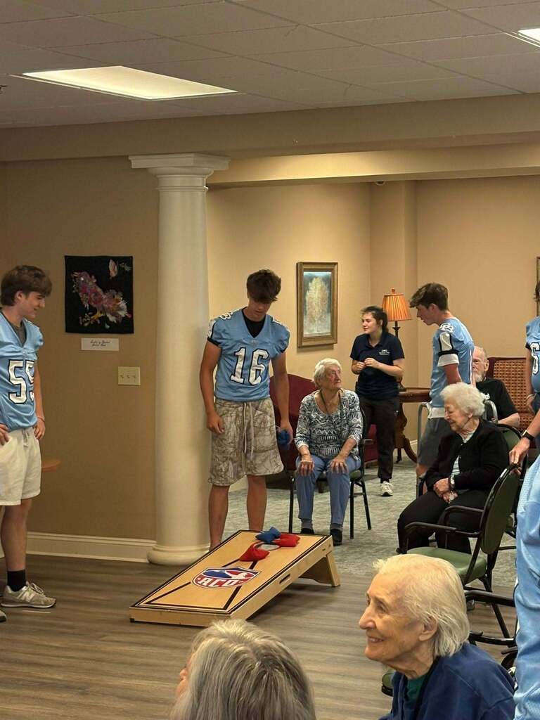 Members of the Boone football team playing cornhole with residents of Keystone Villas