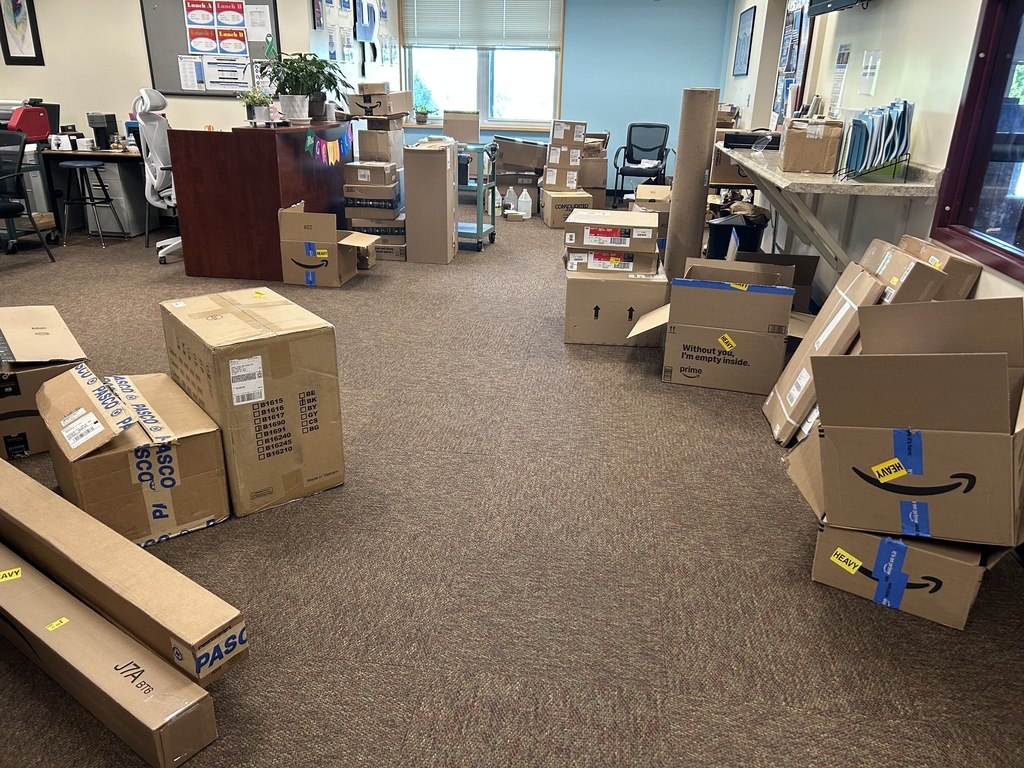Picture of the high school office filled with Amazon and other boxes of school supplies for the start of the new year.
