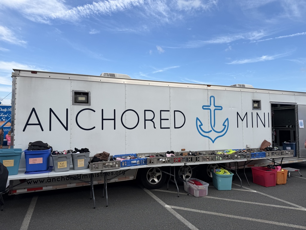 Photo of Anchored ministries mobile clothing closet trailer with tables of shoes, bins of socks, and more.