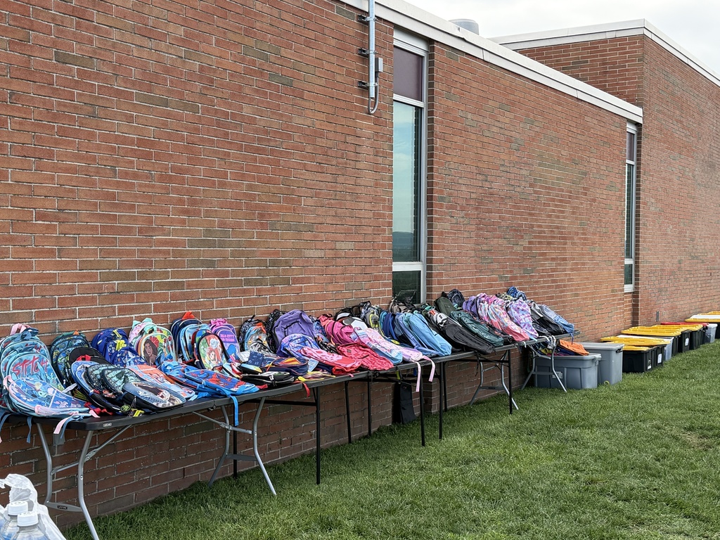 Picture of three tables filled with student backpacks.