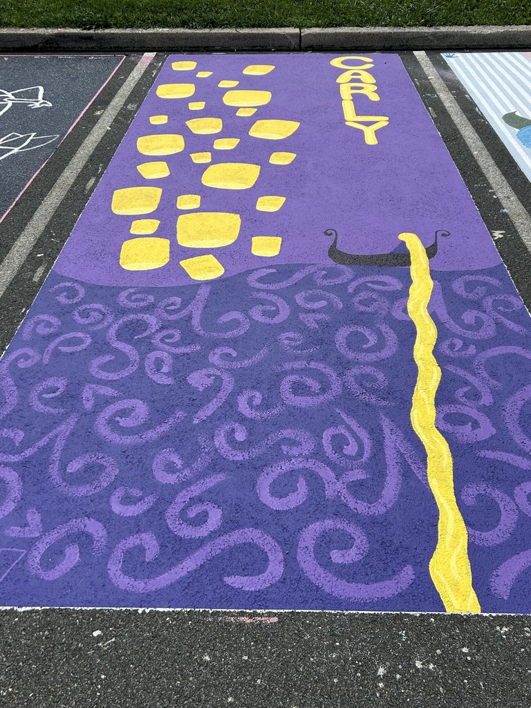 A purple-painted parking spot features yellow letters βCARLY,β scattered yellow shapes, and intricate purple swirls. A black-and-yellow decorative design runs along one side of the space.