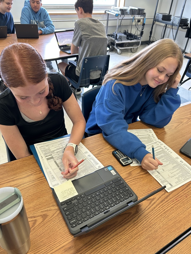 Two high school students work on their tax returns at a classroom.